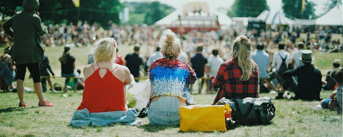 Three women sat on a blanket at a festival
