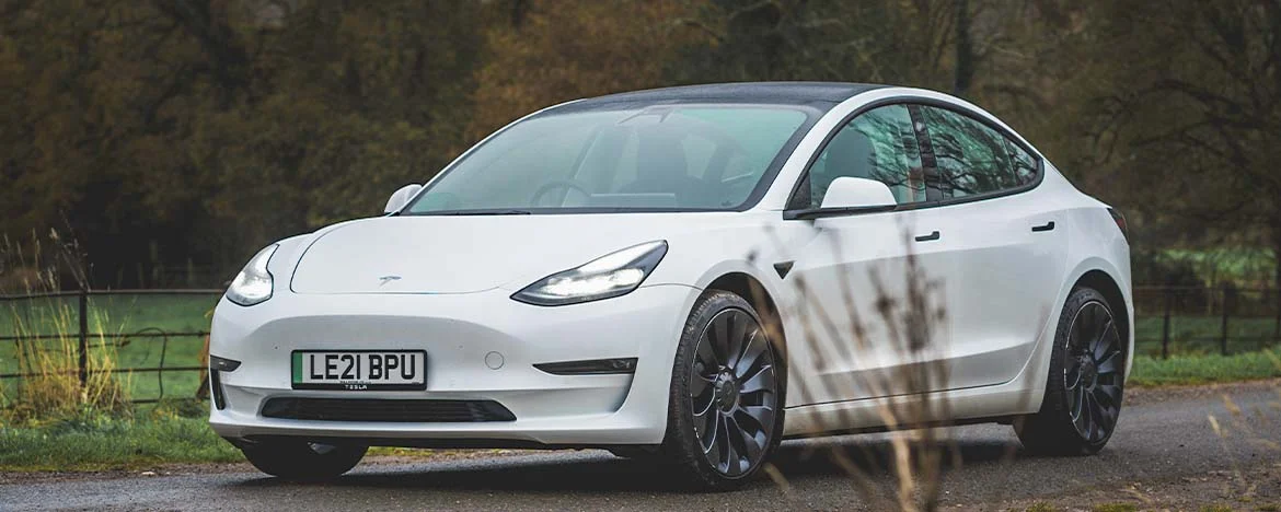 Tesla Model 3 parked by field