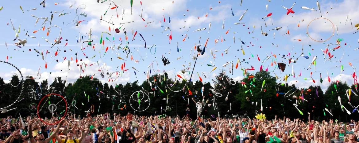 Large crowd at a festival, throwing juggling clubs in the air