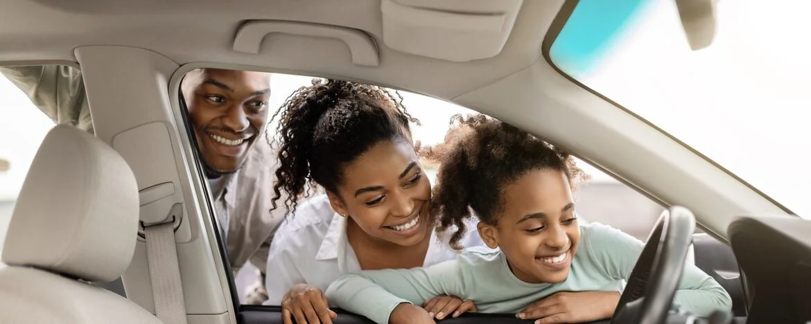 Family looking through front window of their car and smiling