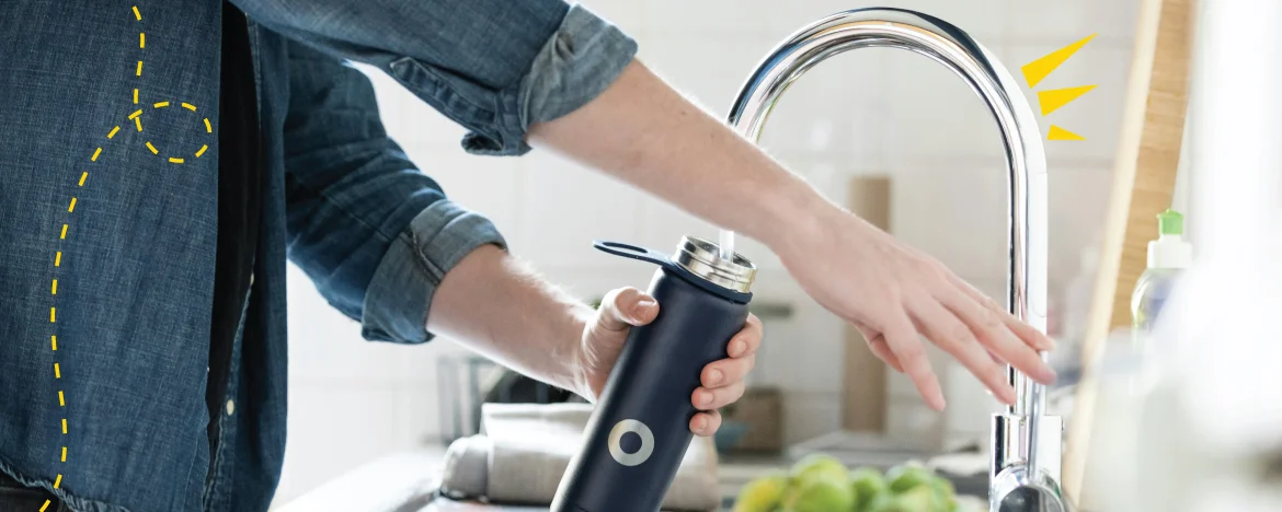 person filling up bottle of water at the tap