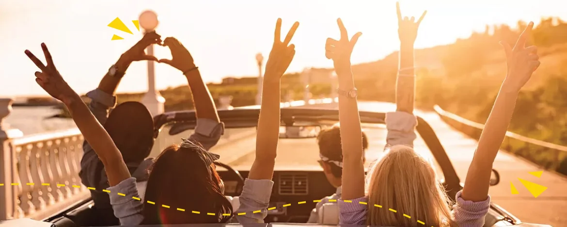 people in car with roof off and arms up