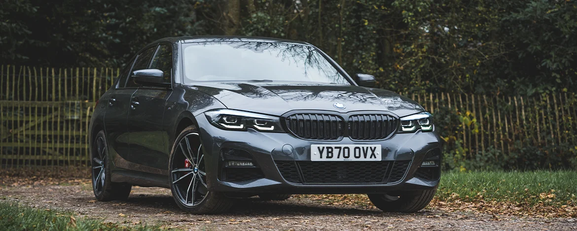 BMW 330e parked by fence