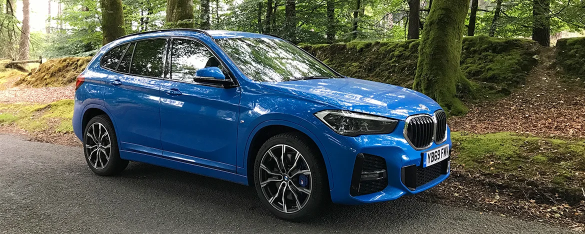 BMW X1 parked in woodland