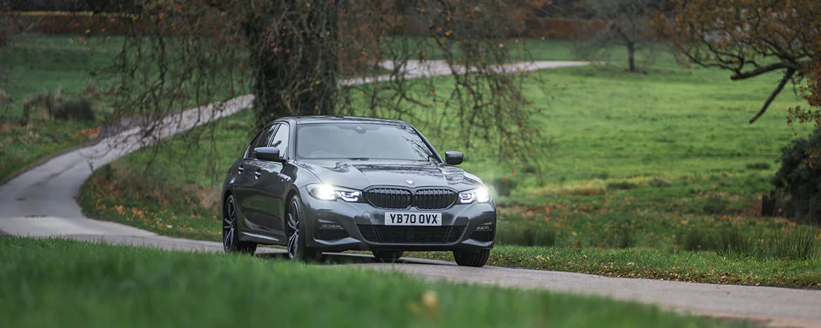 BMW 330e driving past tree