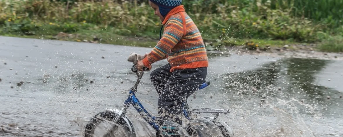 Child on a bicycle riding through a puddle