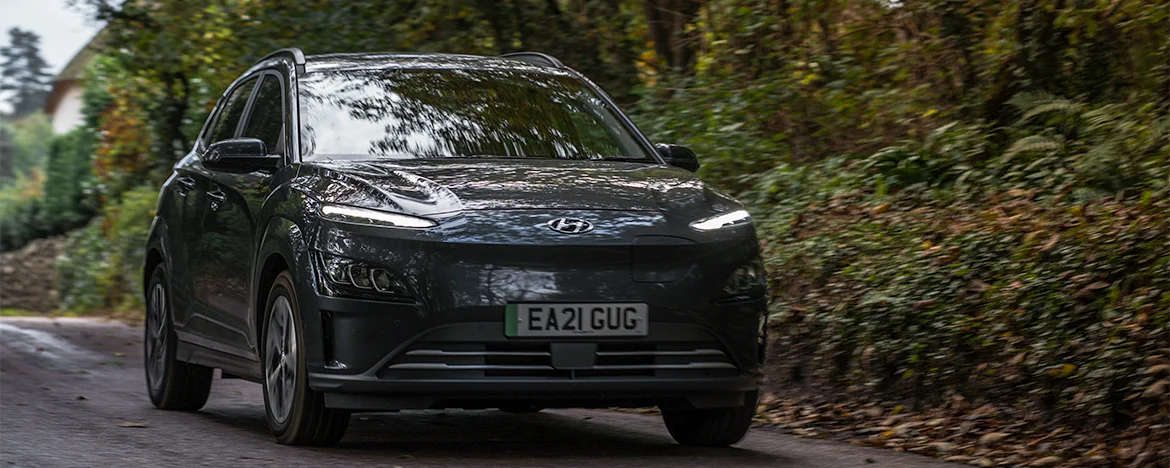 Hyundai Kona Electric driving past trees