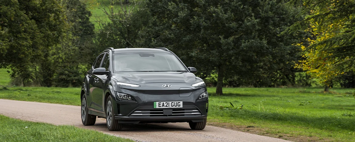 Hyundai Kona Electric driving past tree