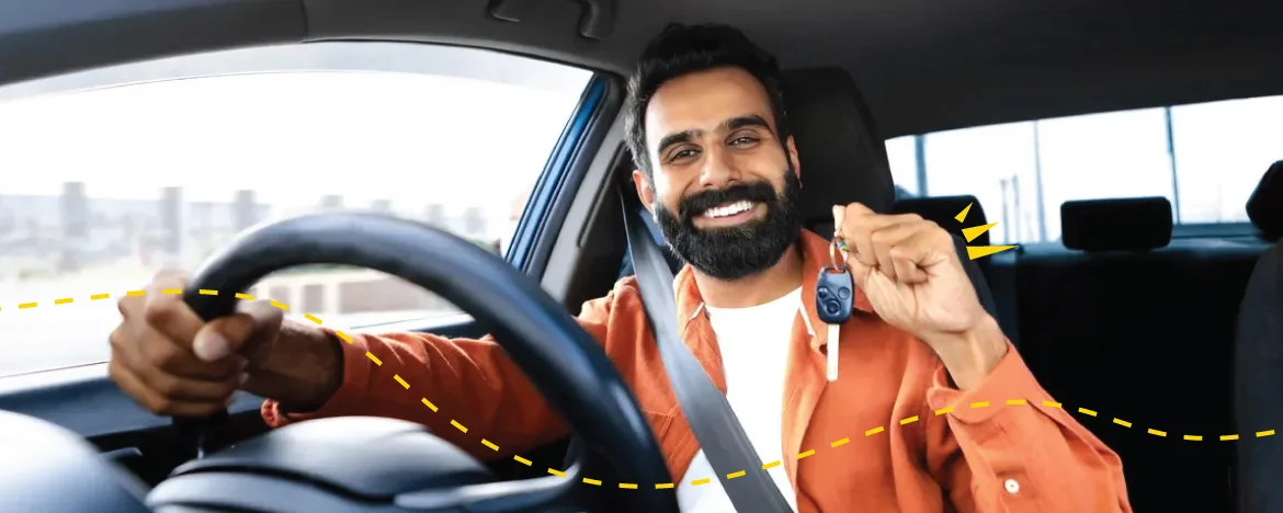 man holding car keys sat at steering wheel of car