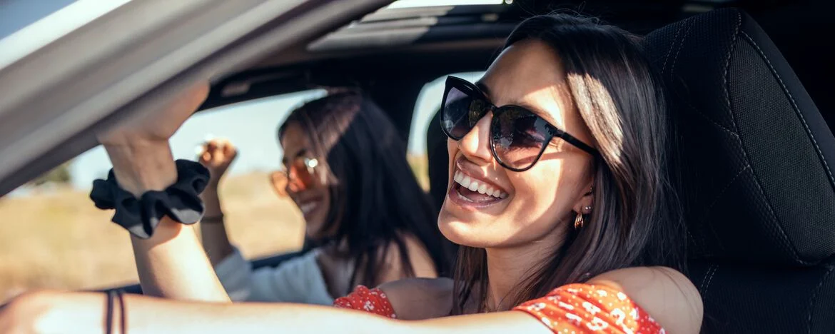 Two smiling girls driving in sunny, country setting