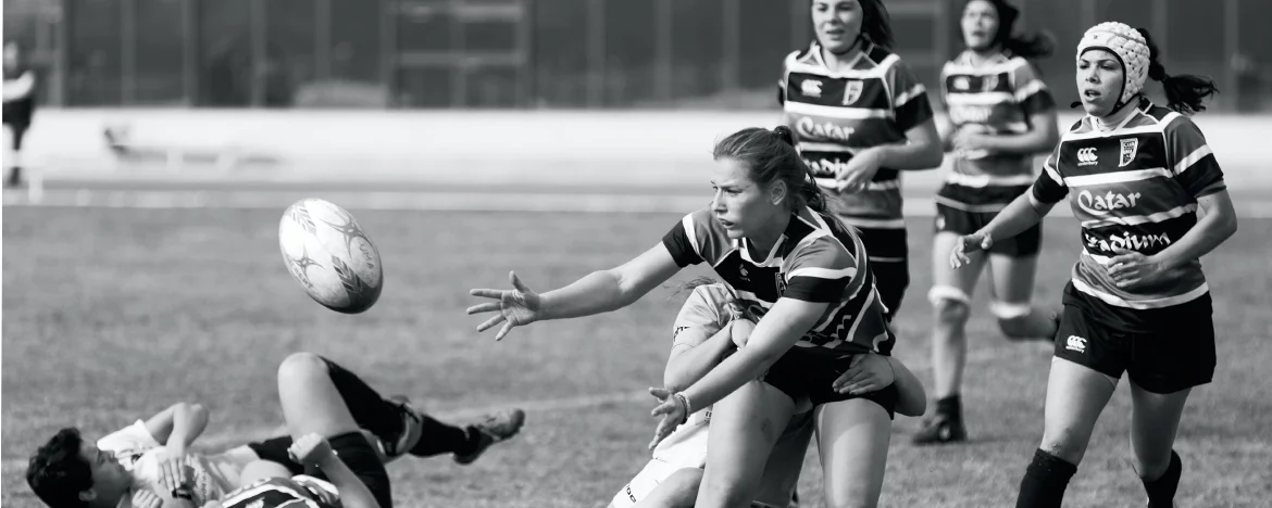 Female rugby players mid-tackle