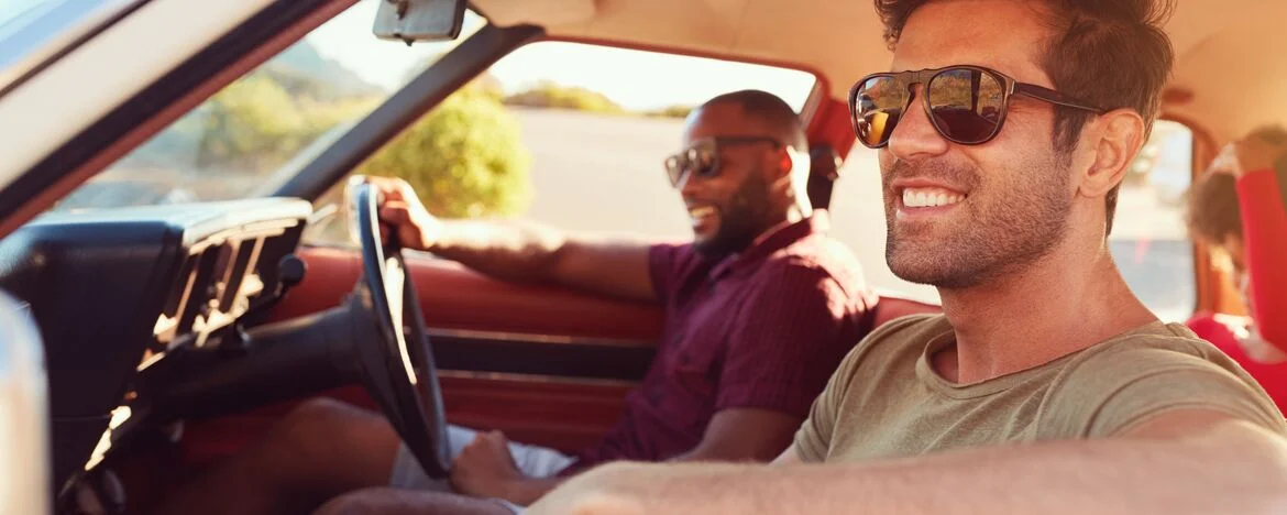 Two men in a car smiling, one man behind the wheel