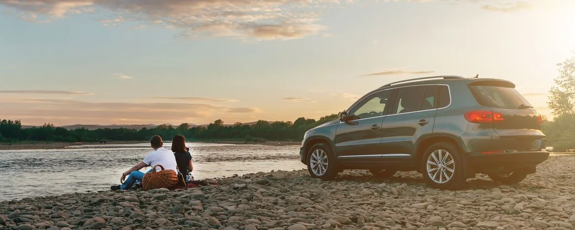 Couple sitting by a lake in front of their car