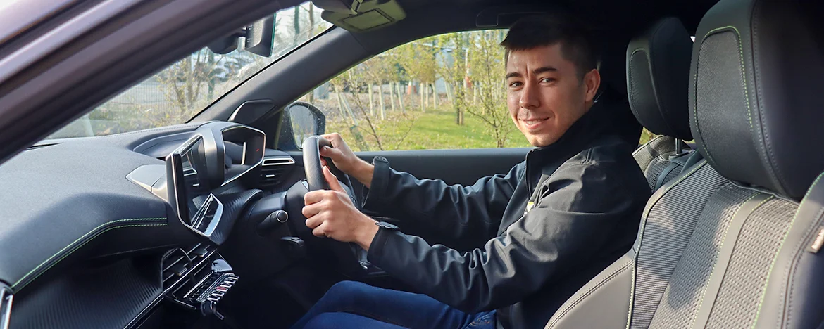 Man smiling at camera whilst sat in the cabin of Peugeot e-2008