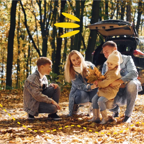 family playing with leaves outside car