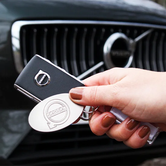 hand holding car keys in front of car