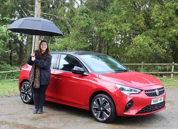 woman with umbrella next to Corsa-e