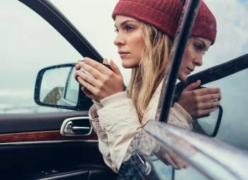 Person sat in front car seat with door open and holding a hot drink