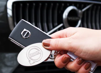 hand holding car keys in front of car