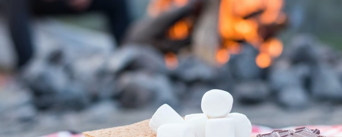The ingredients for smores beside a camp fire