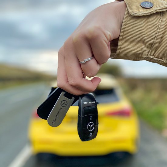 Mercedes-Benz keys in front of yellow car