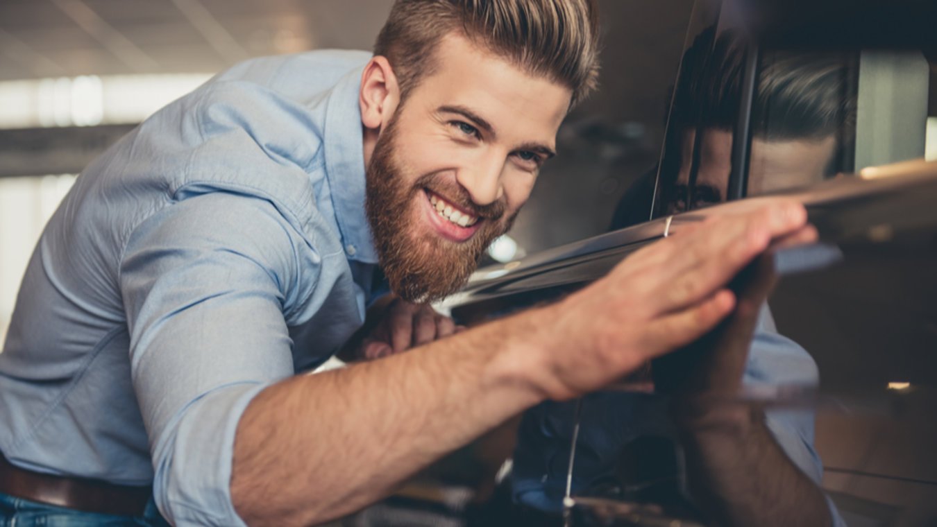 Man leaning against and shining a new car